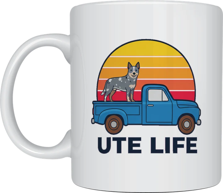 Ute life mug: Cartoon blue ute with a blue heeler cattle dog standing on the tray in front of a striped sunset, above the words Ute Life