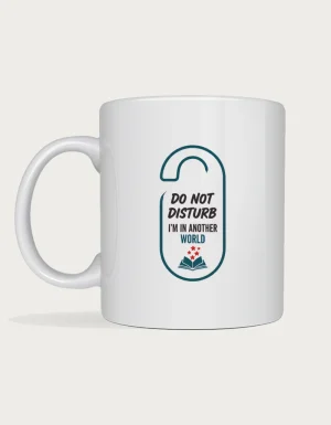 Funny reading mug with a door hanger sign design reading Do Not Disturb, I'm In Another World with a small open book, on a white ceramic mug