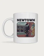 Newtown mug: Retro postcard with the word Newtown above an emo rat in a black hoodie holding a vinyl record against a street art wall, with King Street terrace shops behind