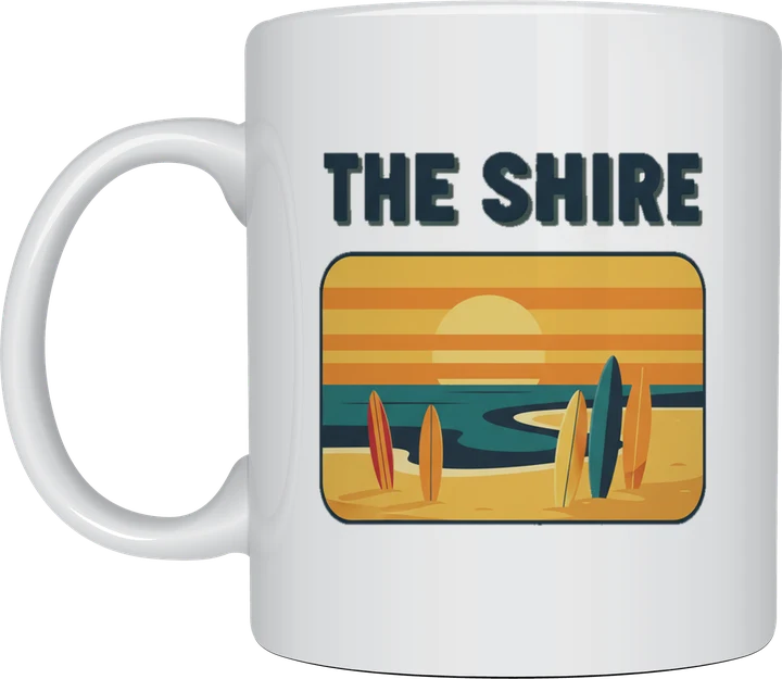 The shire mug: Retro postcard with the words The Shire above a surf beach at sunset with surfboards standing in the sand