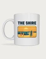 The shire mug: Retro postcard with the words The Shire above a surf beach at sunset with surfboards standing in the sand