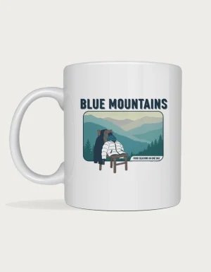 Blue mountains mug: Retro postcard with the words Blue Mountains above misty ridges and a chair piled with jackets, reading Four Seasons in One Day